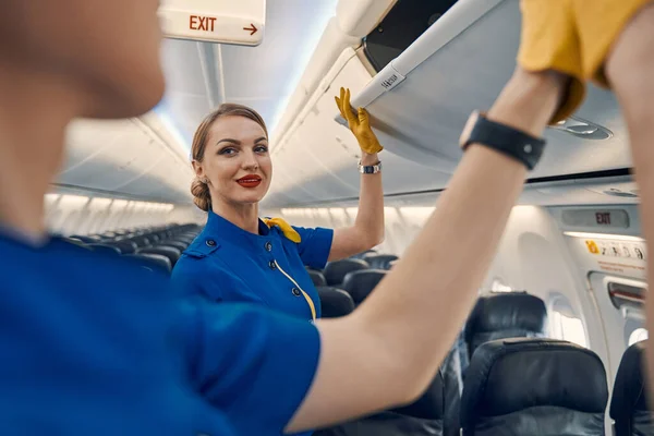 Stewardessen die de bovenliggende kluisjes in de passagierscabine sluiten — Stockfoto