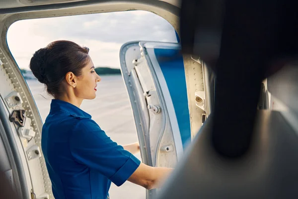 Joven azafata de pie en la puerta del avión —  Fotos de Stock