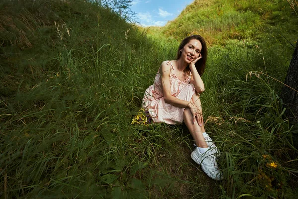 Linda senhora sentada com seu bando de flores na grama — Fotografia de Stock