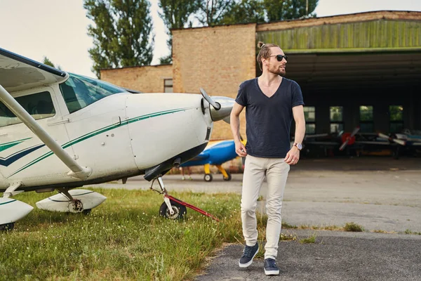 Hombre barbudo guapo caminando cerca de aviones privados —  Fotos de Stock