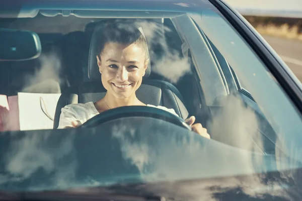 Счастливая женщина за рулем автомобиля и улыбается — стоковое фото