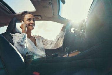 Cep telefonuyla konuşurken araba kullanan bir kadın.