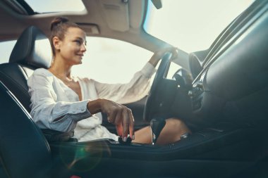 Modern arabadaki kadın şanzıman panelinin düzenleyici düğmesini çeviriyor