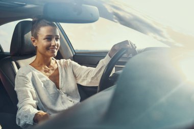 Güneşli bir günde araba süren bir kadın.