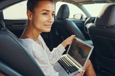 Arabada dizüstü bilgisayarı dışarıda bekleyen endişeli bir kadın.