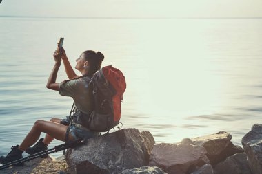Göl kenarında gökyüzünü fotoğraflayan bir kadın.
