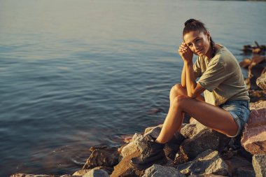 Gölün kıyısında batan güneşe hayran bir kadın.