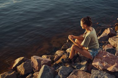 Kayalık kıyı şeridinden suyu izleyen kişi