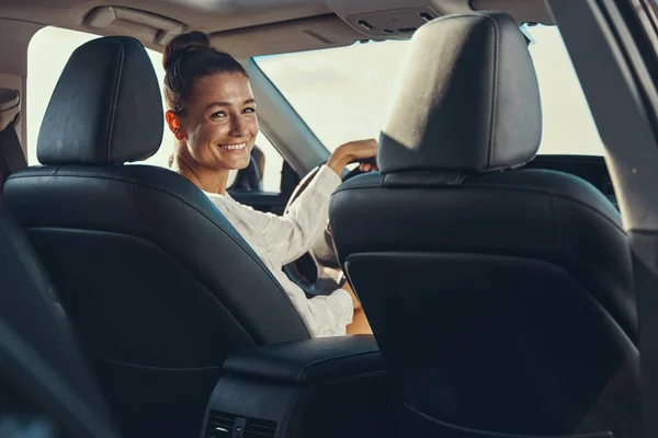 Возбужденная женщина поворачивается на заднее сиденье во время вождения — стоковое фото