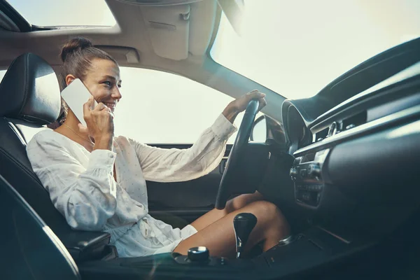 Mulher caucasiana falando ao telefone enquanto dirige — Fotografia de Stock