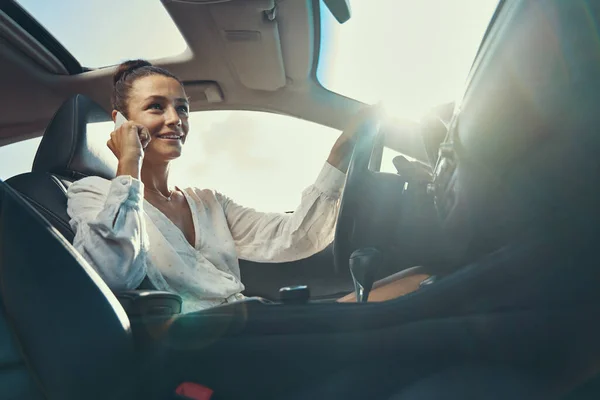 Mulher dirigindo um carro enquanto fala através do telefone móvel — Fotografia de Stock