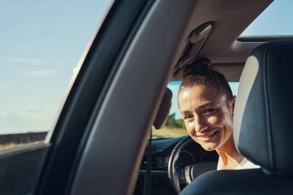 Женщина средних лет подглядывает на задние сиденья с места водителя — стоковое фото