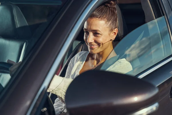 Senhora encantada em um carro durante o pôr do sol — Fotografia de Stock