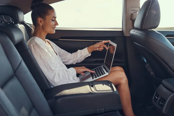 Женщина открывает ноутбук на заднем сидении автомобиля — стоковое фото