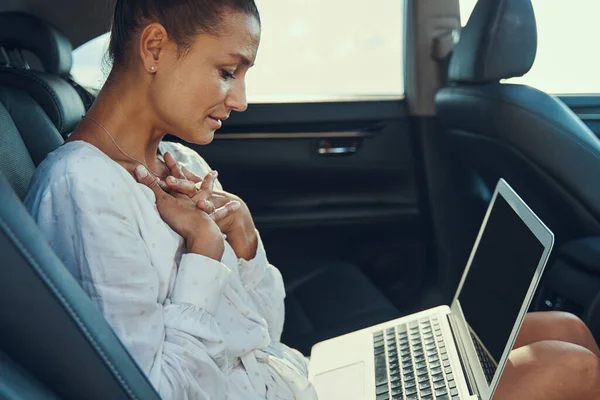 Woman staring at laptop screen while folding hands on chest — Stock Photo, Image