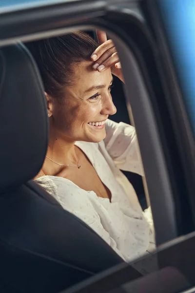 Mulher ajustando seu cabelo enquanto sentada no carro — Fotografia de Stock