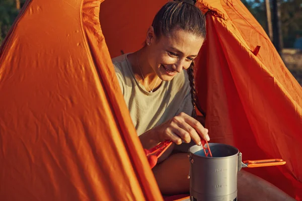 Wanderer mixt im Zelt Tee in großen Becher — Stockfoto
