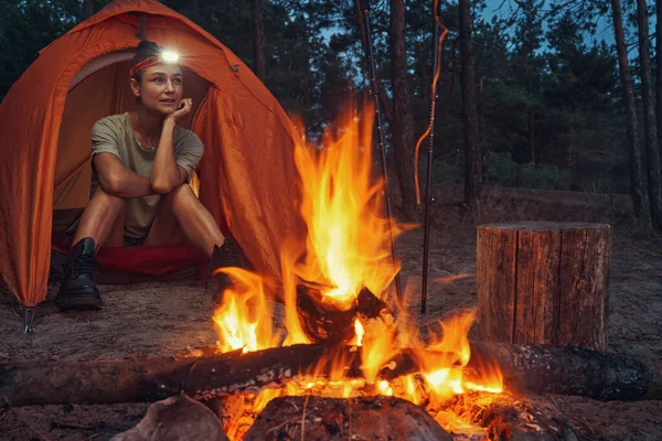 Wanderer schaut sich vom Zelt vor dem Lagerfeuer um — Stockfoto