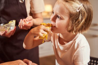 Çocuk hamura bulanmış parmaklarını yalıyor.