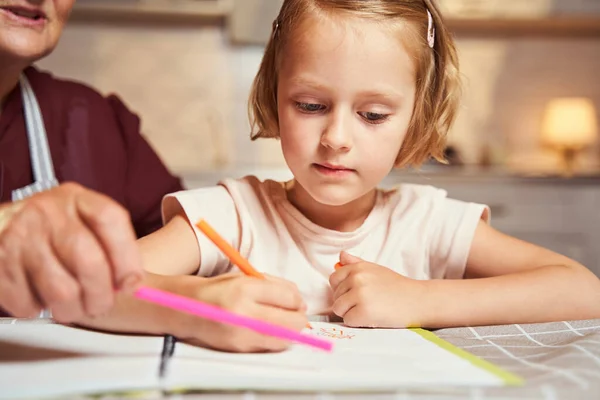 Anciano tomando marcador rosa mientras niña pintando con naranja —  Fotos de Stock