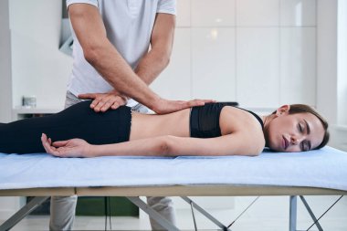 Rehabilitasyon kliniğinde güzel bir bayanın sırtını geren tanınmamış bir osteopat.