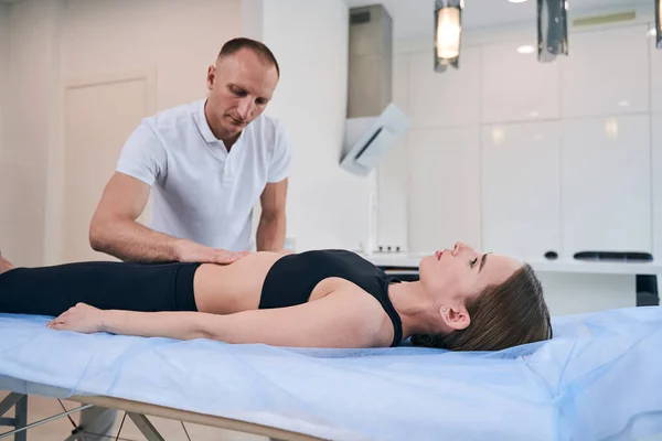 Mooie blanke dame op massage tafel krijgen fysiotherapie sessie in wellness centrum — Stockfoto