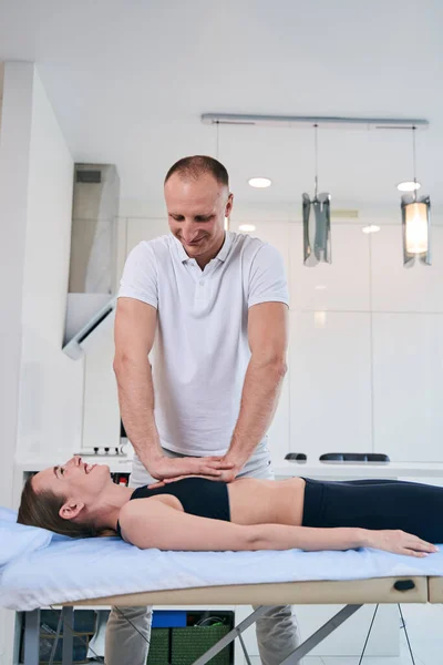 Gelukkig vrolijke vrouw in zwart sportkleding liggend op medische bank — Stockfoto