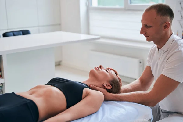 Attractive cute woman in black sportswear relaxing and resting on massage table — Stock Photo, Image