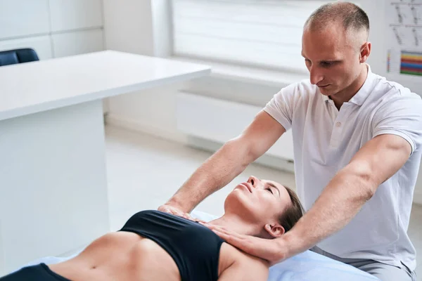 Charmante vrouw liggend op de medische bank, terwijl het krijgen van professionele handmatige therapie in wellness-centrum — Stockfoto