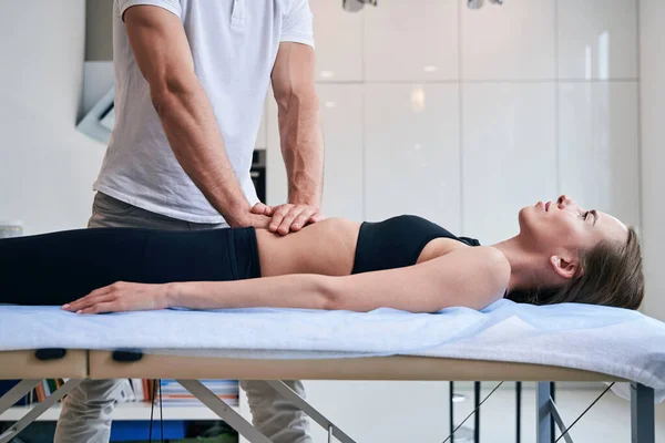 Hermosa mujer elegante en la mesa de masaje recibiendo terapia de masaje en el consultorio médico —  Fotos de Stock