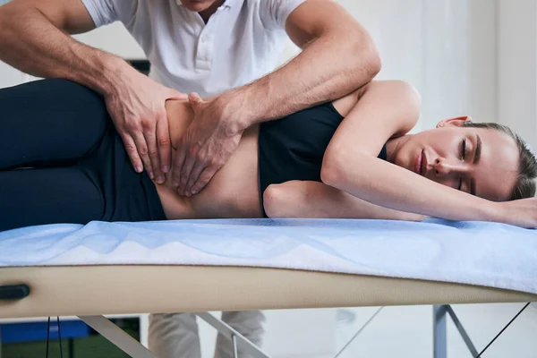 공인되지 않은 남성 물리 치료사가 여성의 위와 함께 의료 실에서 일하는 모습 — 스톡 사진