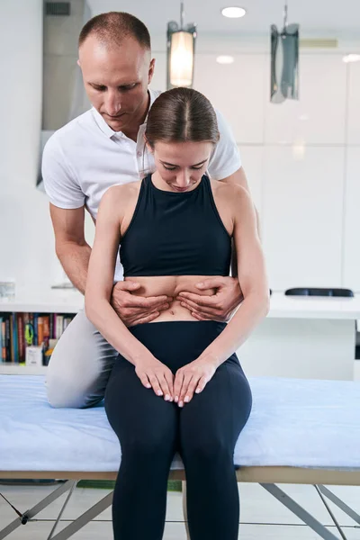 Knappe nette mannelijke osteopaat onderzoeken vrouw buik in medisch kantoor — Stockfoto