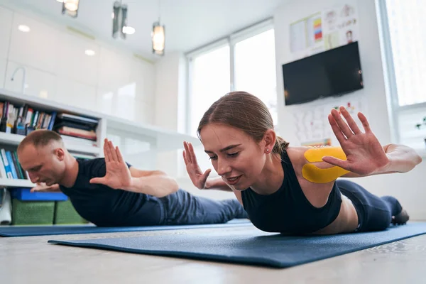 Linda senhora em sportswear com fita amarela no ombro praticando pose de ioga de gafanhoto — Fotografia de Stock