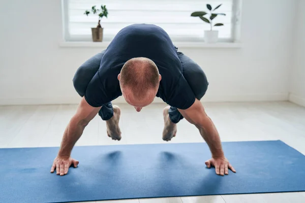 Gimnasta masculino fuerte aseado que equilibra la bandera de la salud con la práctica que estira en clase casera —  Fotos de Stock