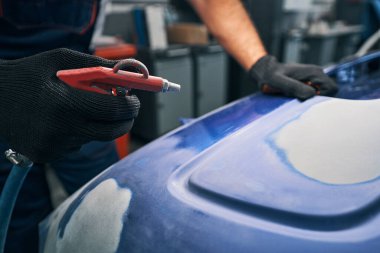 Otomotiv teknisyeni arabayı temizlerken hava tabancasına bastırıyor