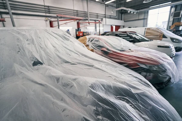 Cars standing in line with dustsheets on them — Stock Photo, Image