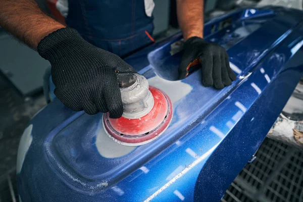 Mechaniker mit Schleifeinheit an blauer Stoßstange — Stockfoto