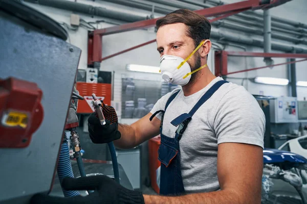 Mechanic hanging air spray gun to metal unit — Stock Photo, Image