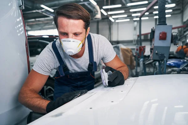 Mecánico de automóviles mirando superficie lijada en taller de reparación de automóviles —  Fotos de Stock