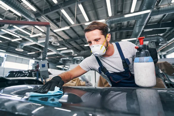 Automobile mechanic wiping dust off a car with cloth — Stock Photo, Image