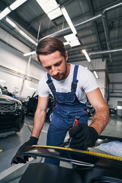 Muž v autoopravně měření automobilové části — Stock fotografie