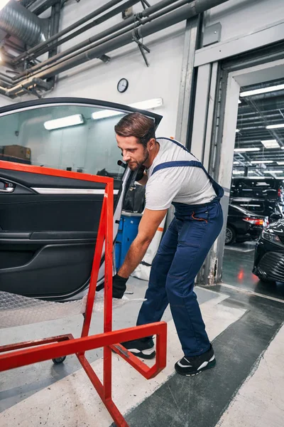 Mężczyzna usługi samochodowe pracownik wprowadzenie drzwi samochodu na czerwony wsparcia — Zdjęcie stockowe