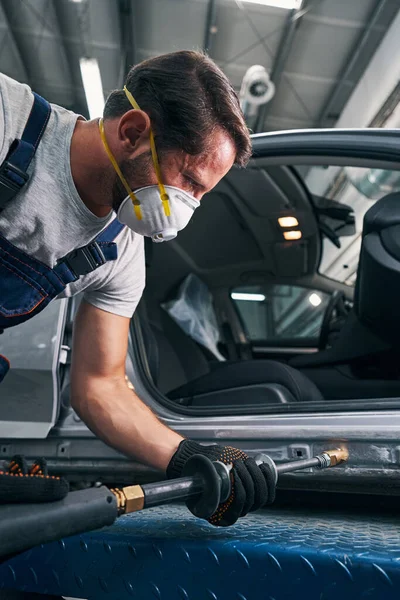 Hombre tenso utilizando martillo deslizante para enderezar la superficie del coche —  Fotos de Stock