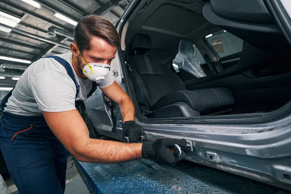 Reparador caucásico colocando una placa de metal sobre el panel lateral —  Fotos de Stock