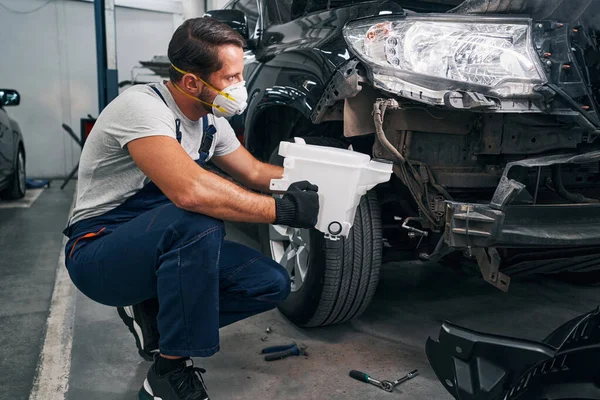 Mechanic is removing washer reservoir from car — Stock Photo, Image