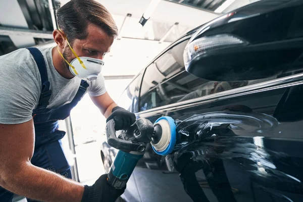 Opravář pomocí leštiče s modrou podložkou na černém automobilu — Stock fotografie