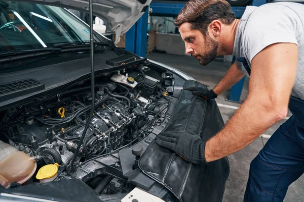 Ung uppmärksam reparatör undersöker bil motor — Stockfoto
