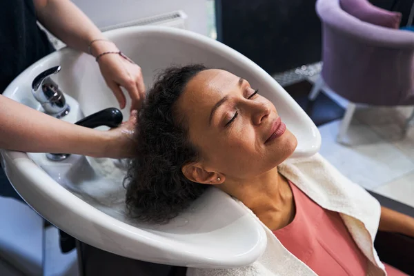 Nöjd kvinna njuter av vårdande förfarande för hår — Stockfoto