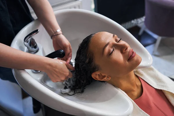 Крупним планом розслаблена жінка миє волосся в салоні — стокове фото