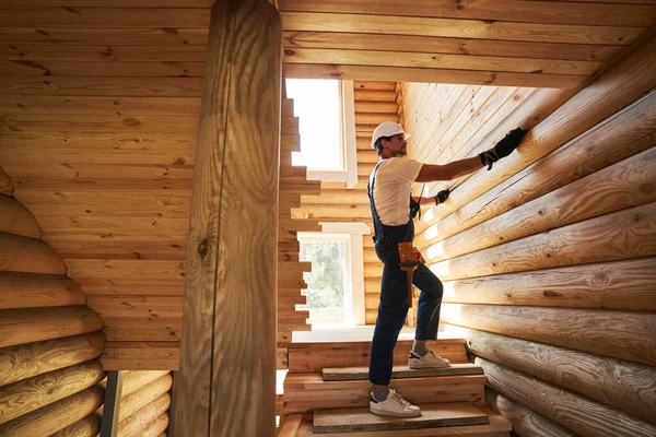 Stavební dělník měří délku stěny kulatiny — Stock fotografie